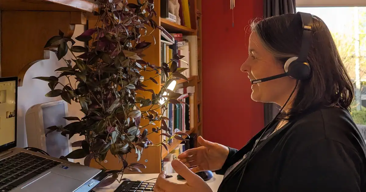 A speech-language pathologist leading a virtual session in front of her computer screen.